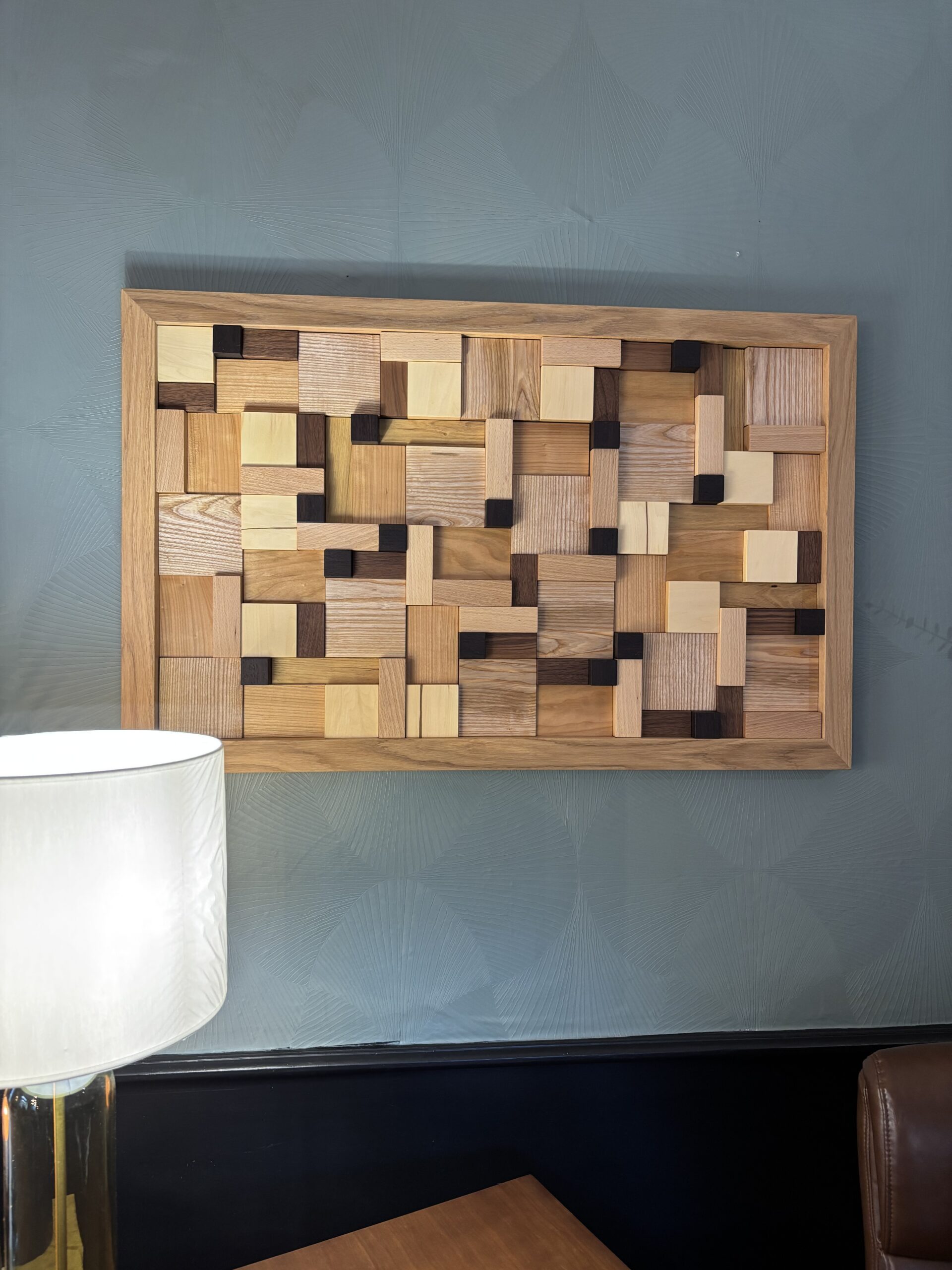 Mur décoratif en bois réalisé par un menuisier en Bretagne, assemblage artisanal de blocs de bois clair et foncé.